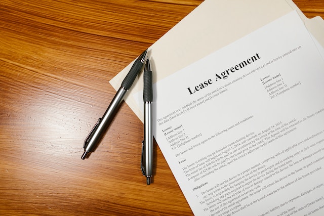 White printed paper that reads "Lease Agreement" in black letters next to two black pens